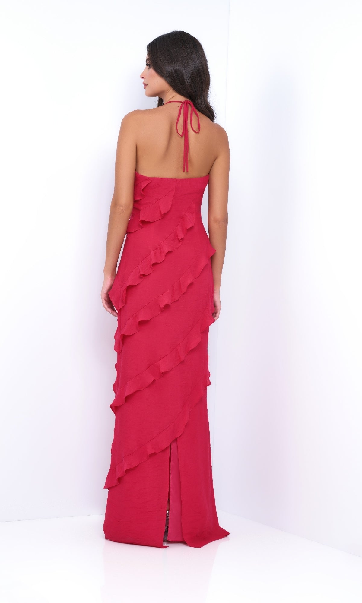 Woman in the Remi by Velvi V-Neck Halter Ruffled Long Prom Dress, floor-length and elegant, stands with her back to the camera against a white background.